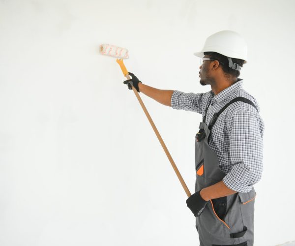 painter man painting the wall, with paint roller.